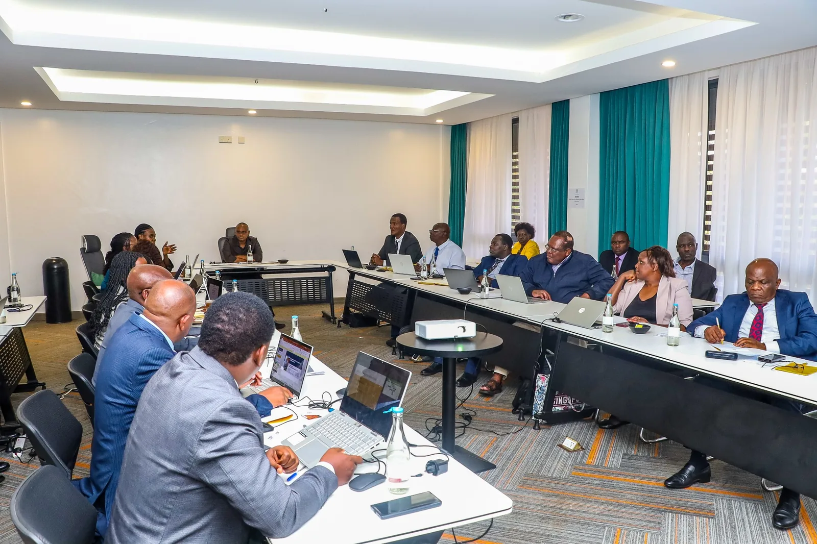 A meeting in progress with participants seated around conference tables.